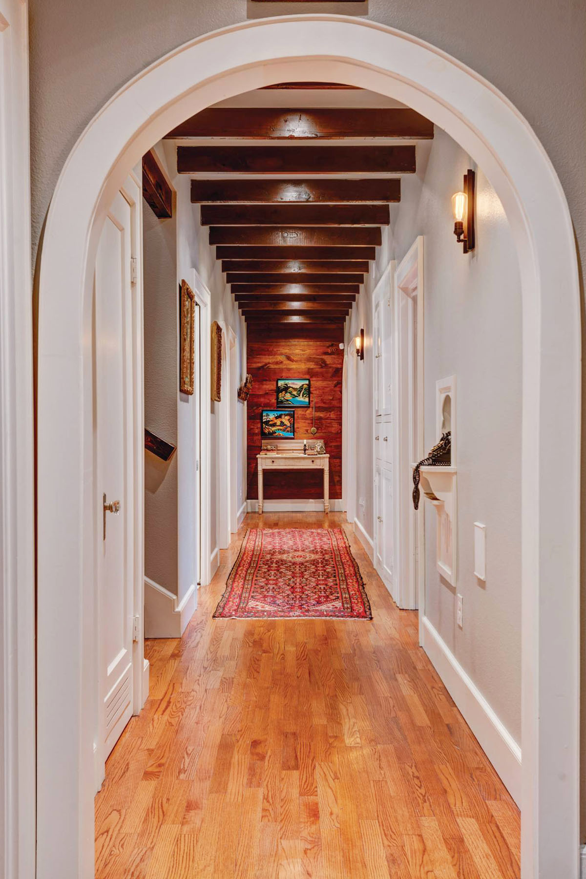 Hallway with Arched Door Opening and Wood Ceiling Beams