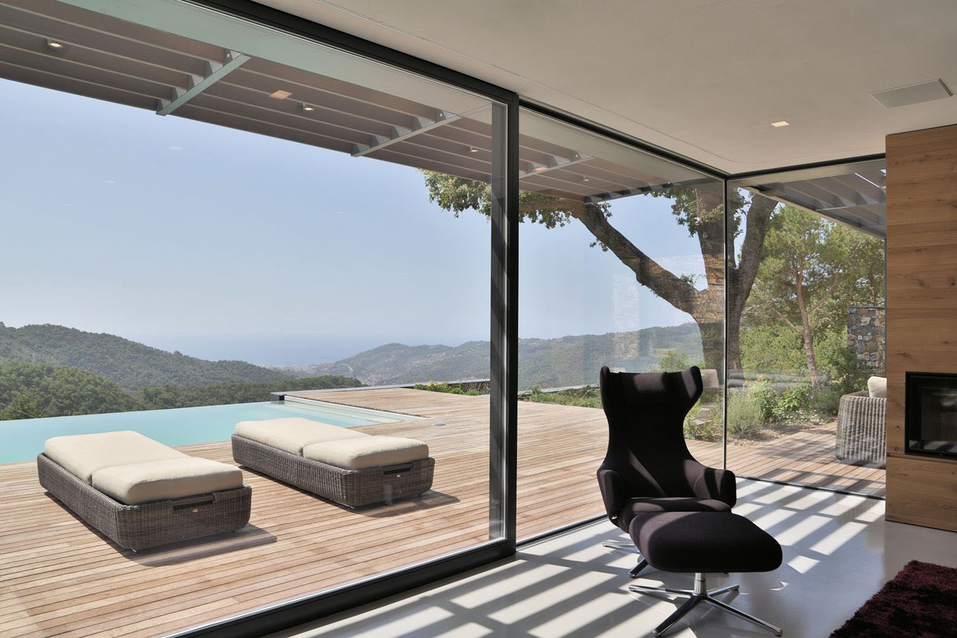 Interior space opening toward the surrounding landscape through large windows.